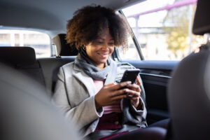 Woman sitting in car looking at cell phone